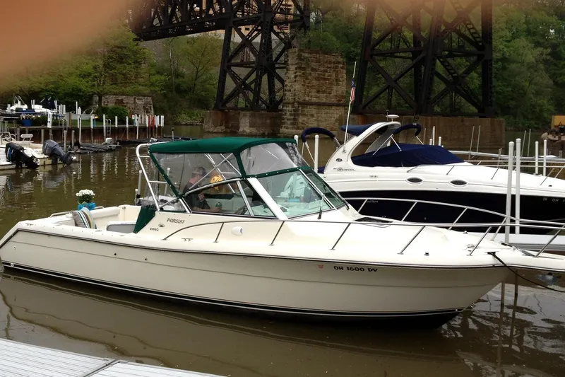 Slide: The Image of 1998 Pursuit 2860 Denali boat docked near a bridge, surrounded by other boats. - 2