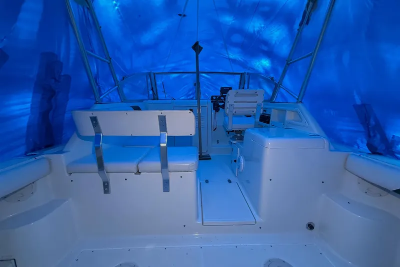 Slide: The Image of 1998 Pursuit 2860 Denali boat interior under blue tarp, featuring seating and helm. - 25
