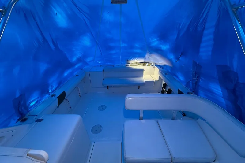 Slide: The Image of 1998 Pursuit 2860 Denali boat interior with blue tarp cover and white seating. - 26