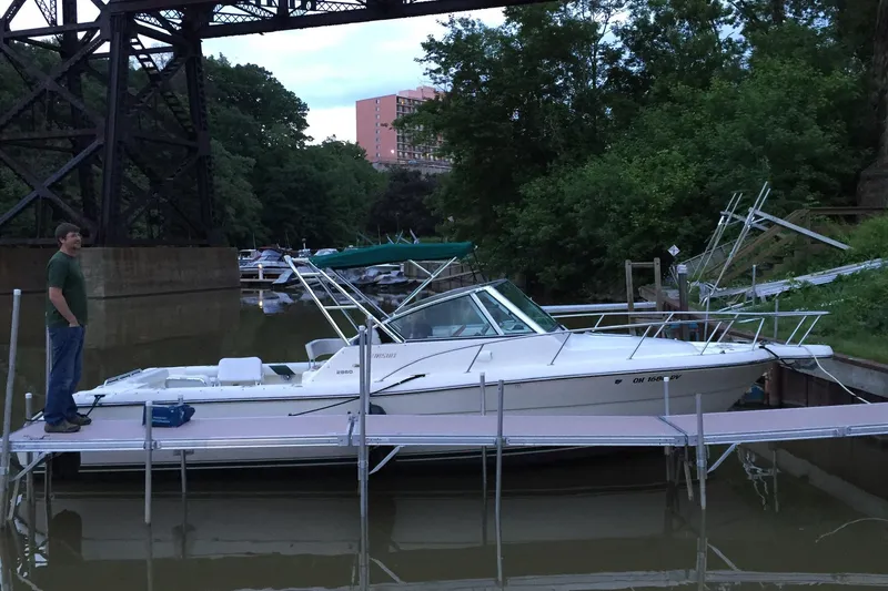 Slide: The Image of 1998 Pursuit 2860 Denali boat docked on a calm river with a person standing nearby. - 3