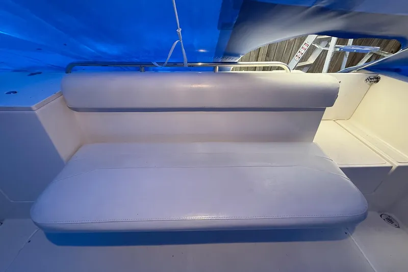Slide: The Image of White cushioned seating on 1998 Pursuit 2860 Denali boat under blue cover. - 31