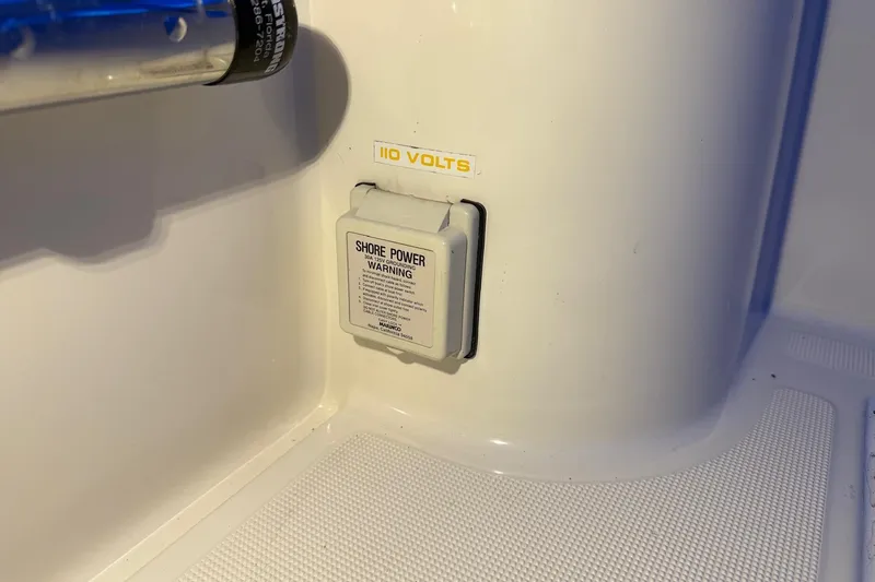 Slide: The Image of 1998 Pursuit 2860 Denali shore power outlet with 110 volts warning label. - 34