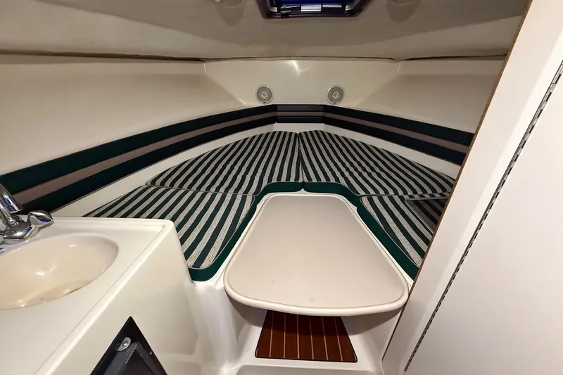 Slide: The Image of 1998 Pursuit 2860 Denali cabin interior with striped cushions and compact sink. - 35
