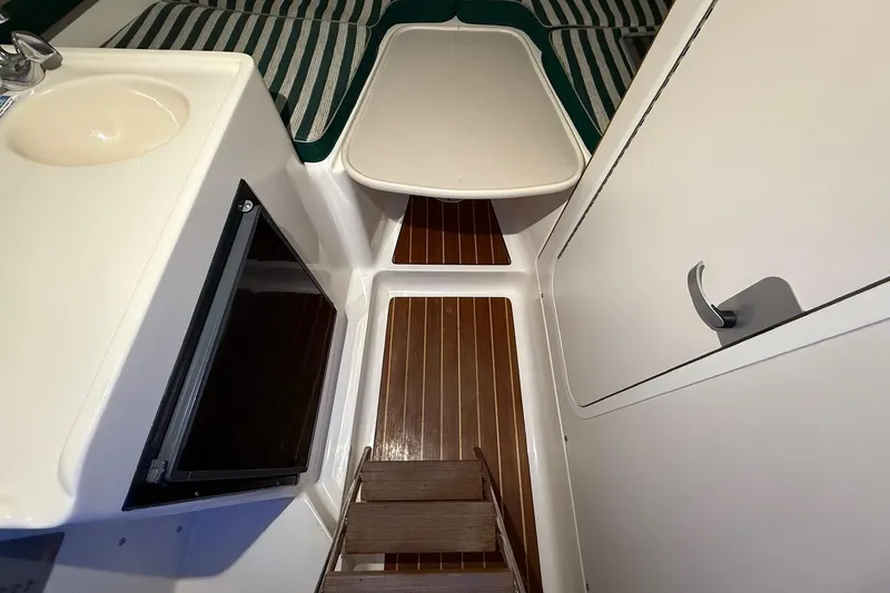 Slide: The Image of 1998 Pursuit 2860 Denali cabin interior with sink, table, and striped cushions. - 40