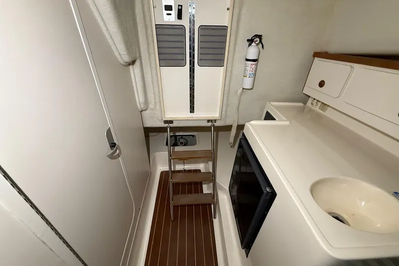 Slide: The Image of 1998 Pursuit 2860 Denali cabin interior with sink, storage, and fire extinguisher. - 43