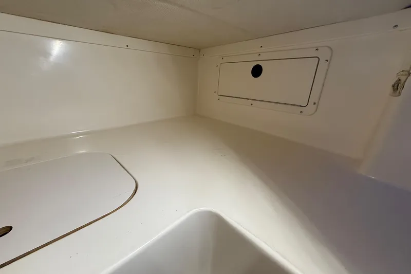 Slide: The Image of Interior view of a 1998 Pursuit 2860 Denali boat, featuring a clean, white storage compartment. - 47