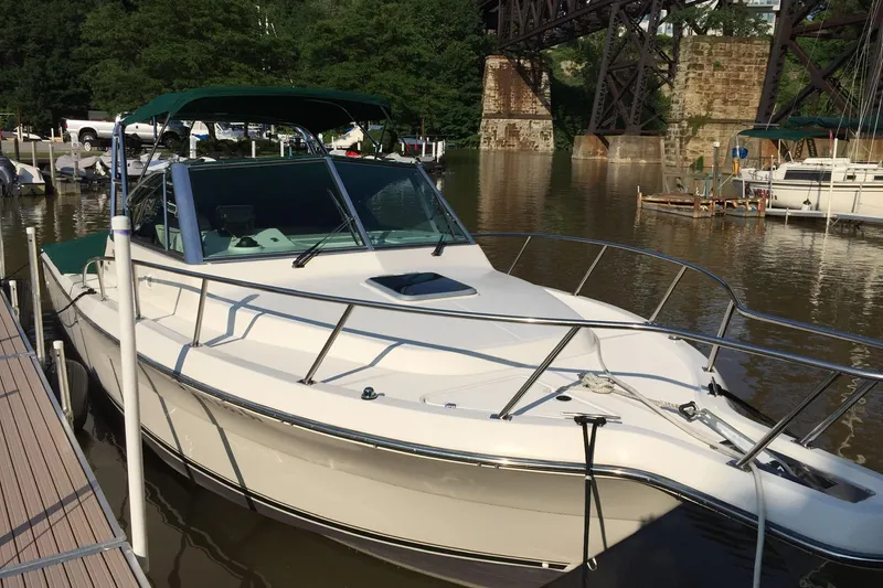 Slide: The Image of 1998 Pursuit 2860 Denali boat docked by a river with lush greenery. - 6