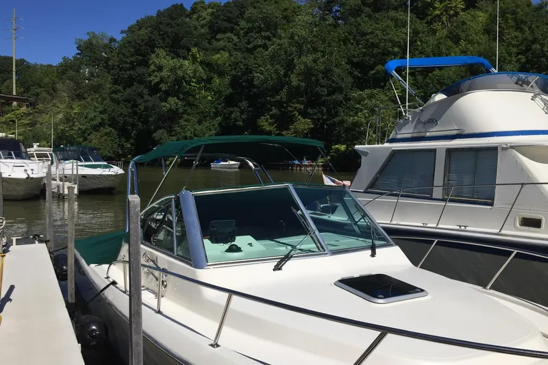 Slide: The Image of 1998 Pursuit 2860 Denali boat docked near lush green trees. - 7