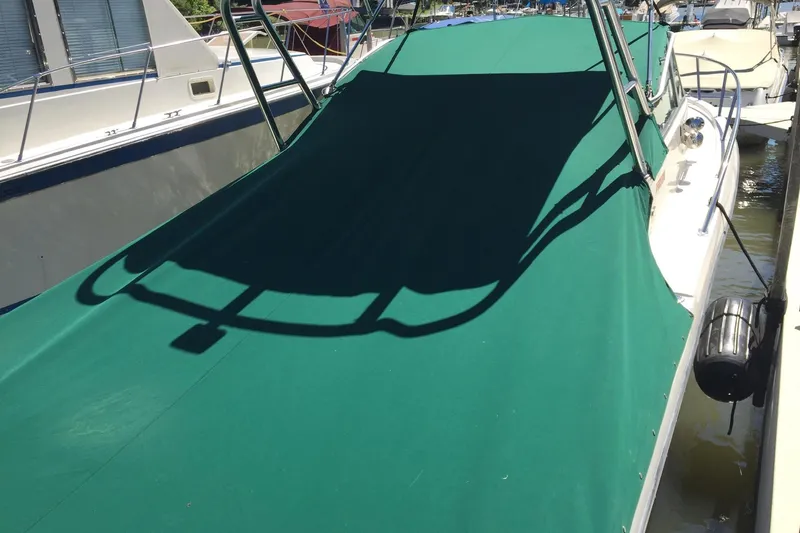 Slide: The Image of 1998 Pursuit 2860 Denali boat with green cover docked at marina. - 8