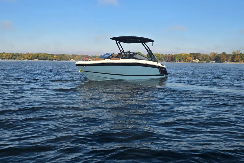 Slide: The Image of 2022 Cobalt R4 Surf boat cruising on a serene lake under a clear blue sky. - 34