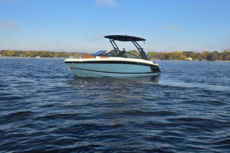 Slide: The Image of 2022 Cobalt R4 Surf boat on a calm lake under a clear blue sky. - 36