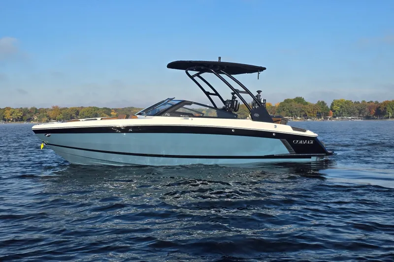 Slide: The Image of 2022 Cobalt R4 Surf boat on a calm lake with trees in the background. - 39