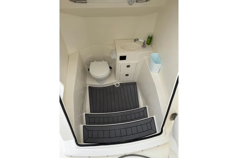 Slide: The Image of 2023 Cobia 301 Center Console interior with toilet, sink, and non-slip flooring. - 11