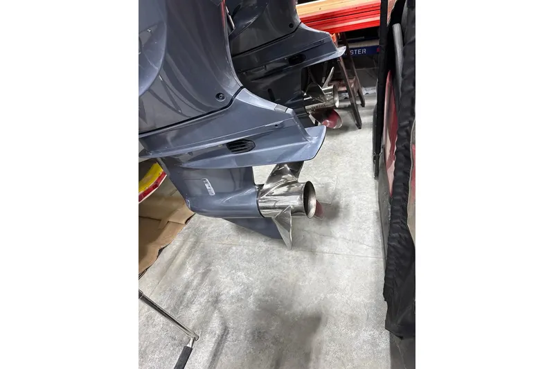 Slide: The Image of 2023 Cobia 301 Center Console boat engines with stainless steel propellers in a workshop. - 2