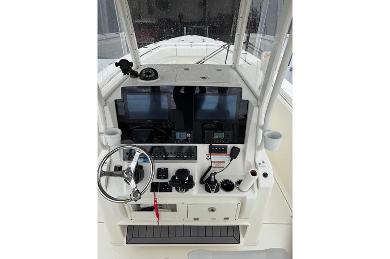 Slide: The Image of 2023 Cobia 301 Center Console boat dashboard with steering wheel and navigation screens. - 5