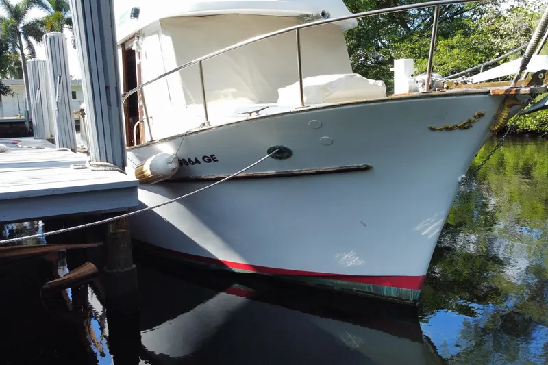 Slide: The Image of 1974 CHB 34 boat docked, white hull, calm water reflection, sunny day. - 11