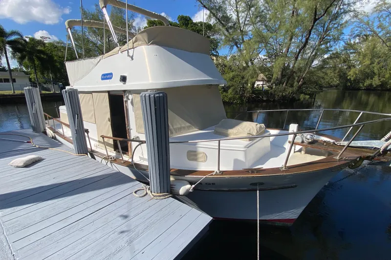 Slide: The Image of 1974 CHB 34 boat docked by a serene riverside with lush greenery. - 13