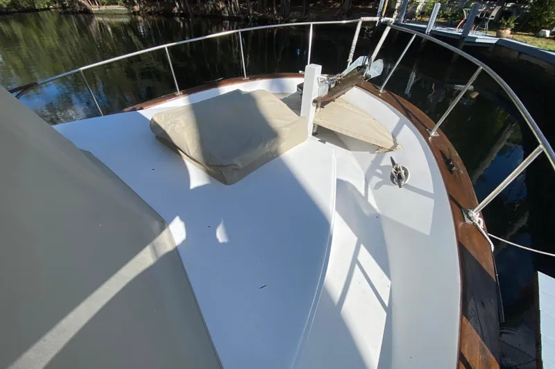 Slide: The Image of 1974 CHB 34 boat deck with railing, cushions, and anchor, docked by calm water. - 15