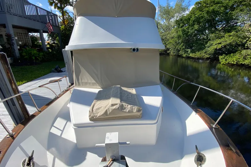 Slide: The Image of 1974 CHB 34 boat docked by a lush riverside, featuring a covered deck area. - 19