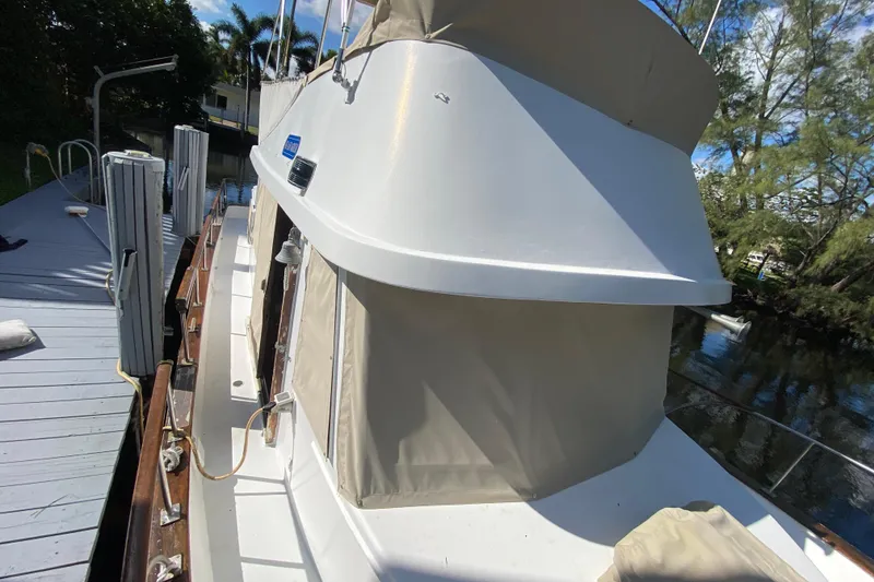 Slide: The Image of 1974 CHB 34 boat docked by a wooden pier, surrounded by trees and water. - 22