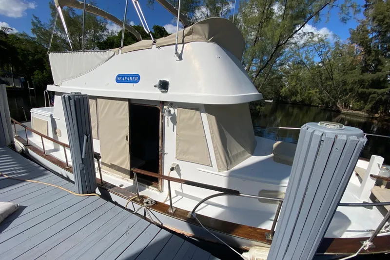 Slide: The Image of 1974 CHB 34 boat docked, featuring beige canvas covers and wooden railings. - 23