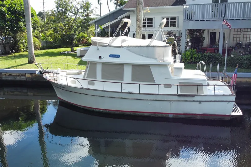 Slide: The Image of 1974 CHB 34 boat docked by a canal, surrounded by lush greenery and residential homes. - 3