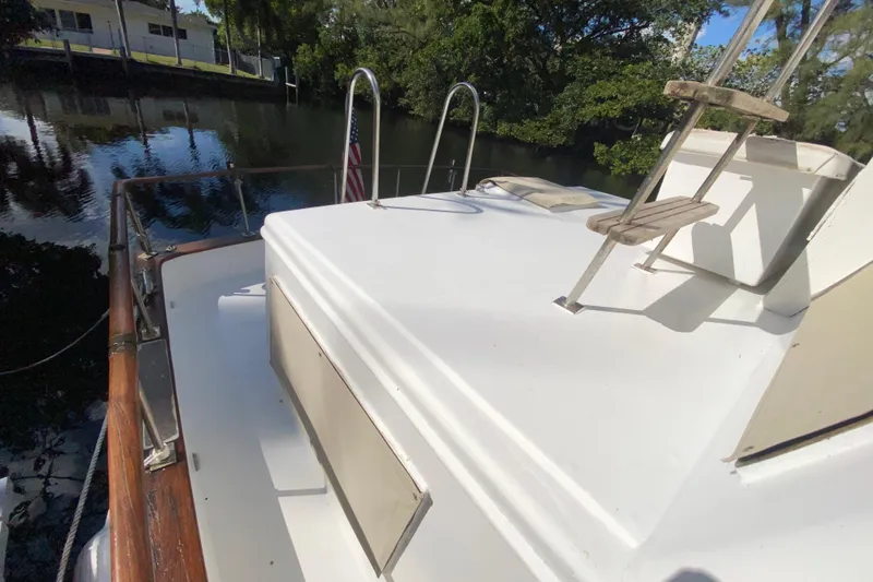 Slide: The Image of 1974 CHB 34 boat deck with ladder, docked by a serene waterway. - 53
