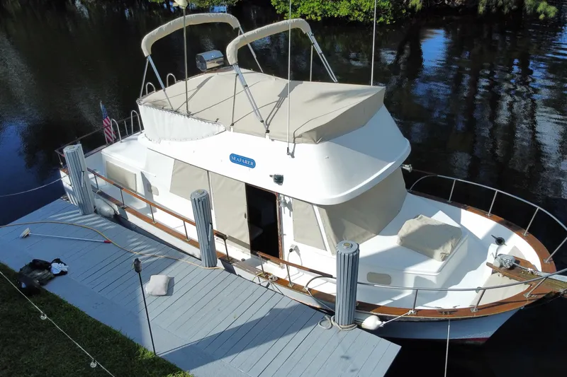 Slide: The Image of 1974 CHB 34 boat docked on calm water, featuring beige canopy and wooden railings. - 8