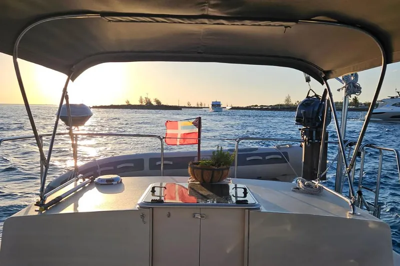 Slide: The Image of 2004 Albin 30 Family Cruiser at sunset, ocean view with flag and canopy. - 12