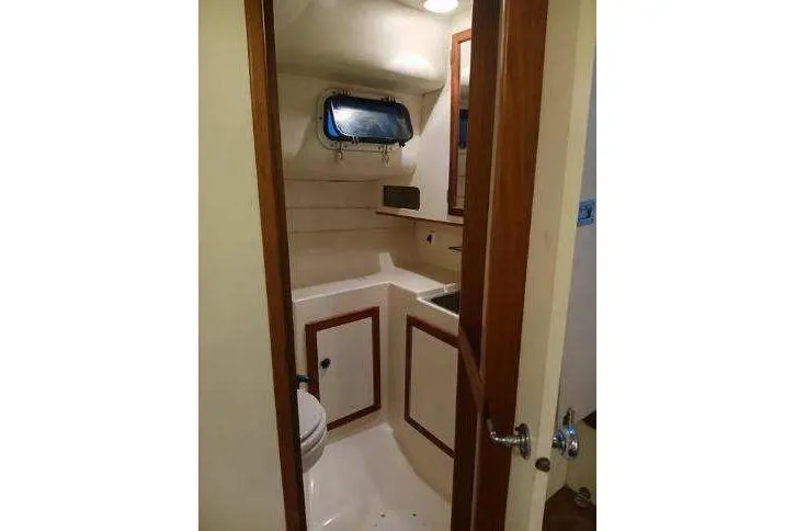 Slide: The Image of 2004 Albin 30 Family Cruiser bathroom with sink, toilet, and porthole window. - 14