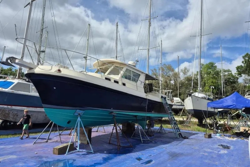 Slide: The Image of 2004 Albin 30 Family Cruiser on stands in a boatyard under cloudy skies. - 16