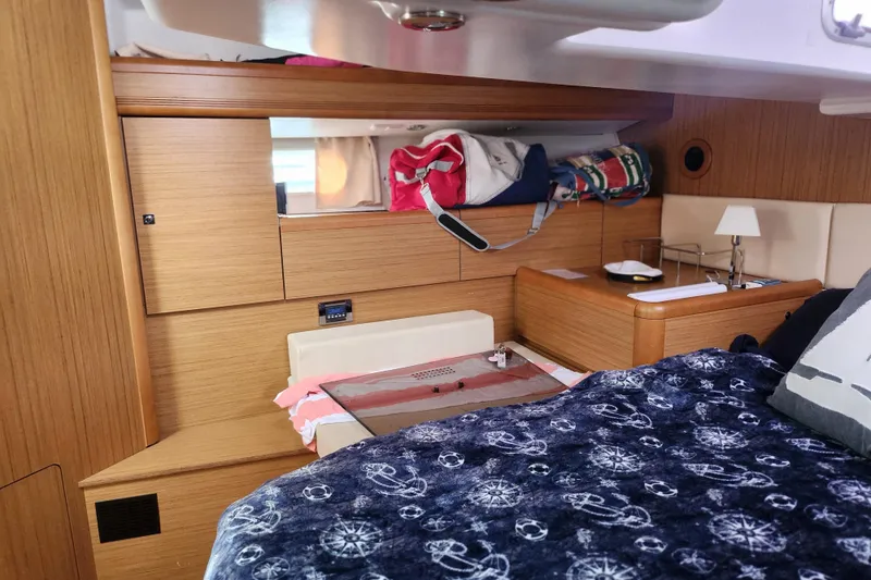 Slide: The Image of Interior cabin of 2010 Jeanneau Sun Odyssey 45 DS yacht, featuring cozy bedding and wooden furnishings. - 32