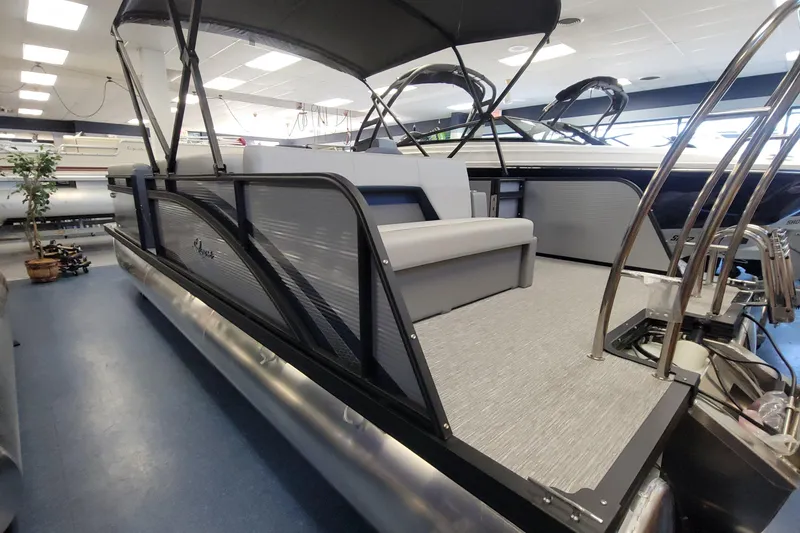 The Image of 2025 Qwest 22 Lanai E-Class TriToon boat in showroom, featuring sleek design and modern seating. - 1
