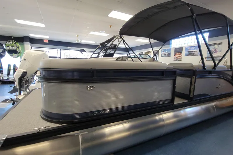 Slide: The Image of 2025 Qwest 22 Lanai E-Class TriToon boat displayed indoors, featuring sleek design and canopy. - 11