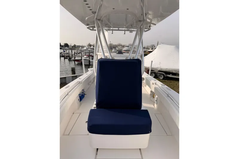 Slide: The Image of Contender boat with blue cushioned seat, docked at marina with covered boats. - 14