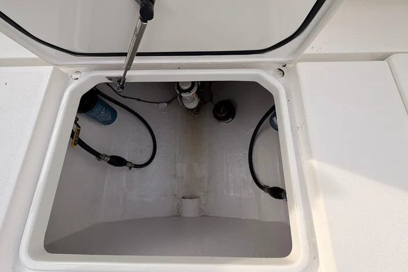 Slide: The Image of Open storage compartment on a Contender boat with visible hoses and fittings. - 22