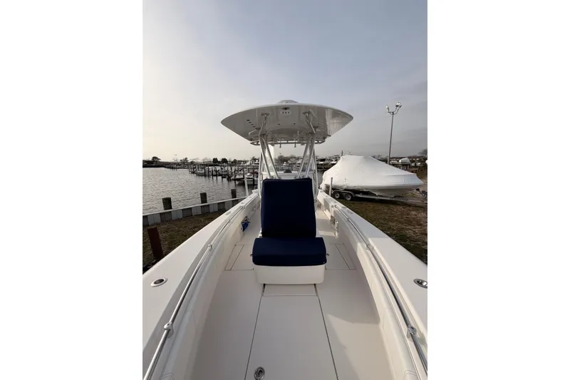 Slide: The Image of Contender boat with blue seating, docked near a marina under a cloudy sky. - 4