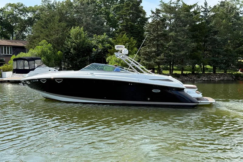 The Image of 2013 Cobalt 323 boat on a serene lake with lush greenery in the background. - 0