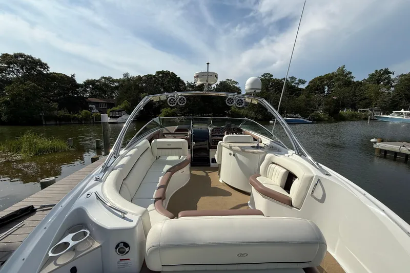 Slide: The Image of 2013 Cobalt 323 boat with spacious seating, docked by a scenic riverside. - 4