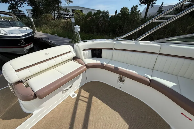 Slide: The Image of 2013 Cobalt 323 boat interior with white and brown seating, docked near greenery. - 7