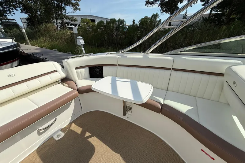 Slide: The Image of 2013 Cobalt 323 boat interior with white and brown seating, small table, and outdoor setting. - 8