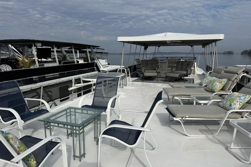 Slide: The Image of 1995 Stardust Cruisers 16x75 houseboat deck with lounge chairs and canopy, under a cloudy sky. - 16