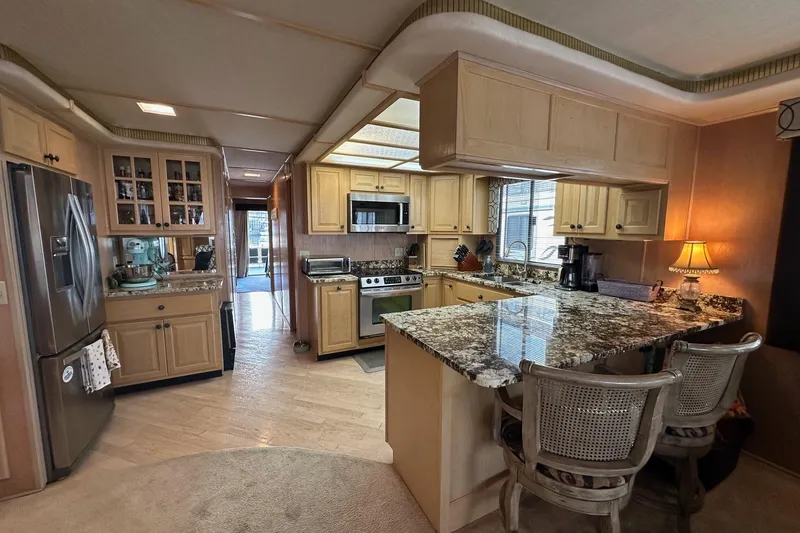 Slide: The Image of Luxurious kitchen in a 1995 Stardust Cruisers 16x75 houseboat with granite countertops and modern appliances. - 4