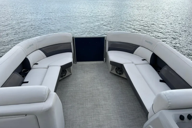Slide: The Image of 2023 Harris Cruiser 230 pontoon boat interior with plush seating on a calm lake. - 10