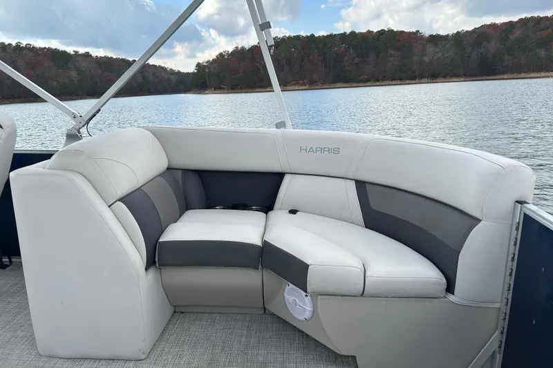 Slide: The Image of 2023 Harris Cruiser 230 boat interior with white and gray seating on a serene lake. - 14
