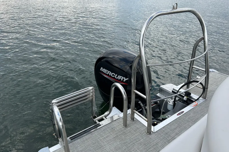 Slide: The Image of 2023 Harris Cruiser 230 boat with Mercury outboard motor and swim ladder on water. - 15