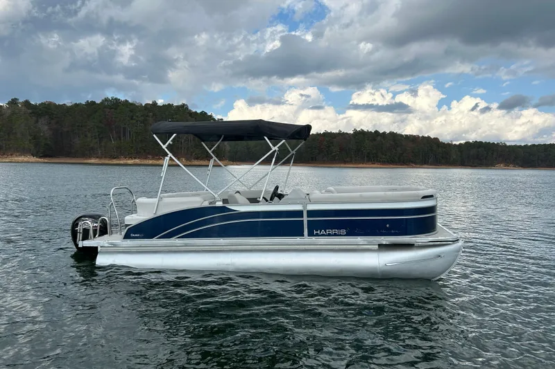 Slide: The Image of 2023 Harris Cruiser 230 pontoon boat on a lake under cloudy skies. - 4