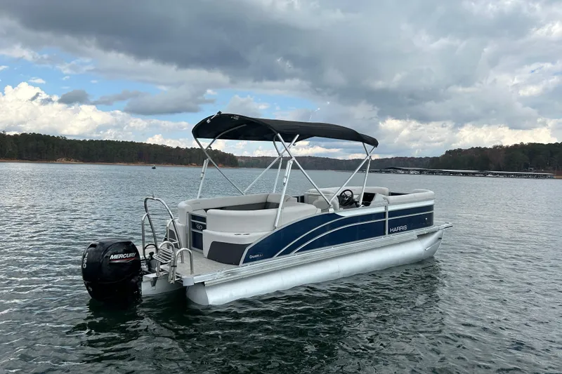 Slide: The Image of 2023 Harris Cruiser 230 pontoon boat on a lake under cloudy skies. - 5