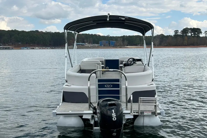 Slide: The Image of 2023 Harris Cruiser 230 pontoon boat on a serene lake with scenic background. - 6