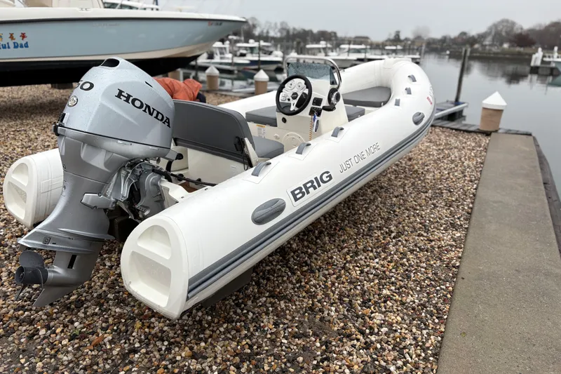 Slide: The Image of 2022 Brig Falcon Tender 420 with Honda outboard motor docked by a marina. - 2